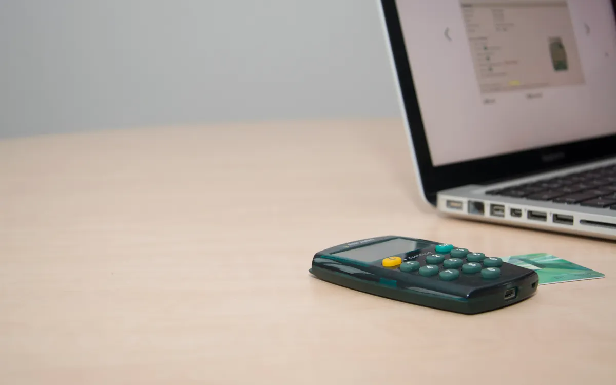 Calculadora, tarjeta y ordenador portátil sobre una mesa de trabajo
